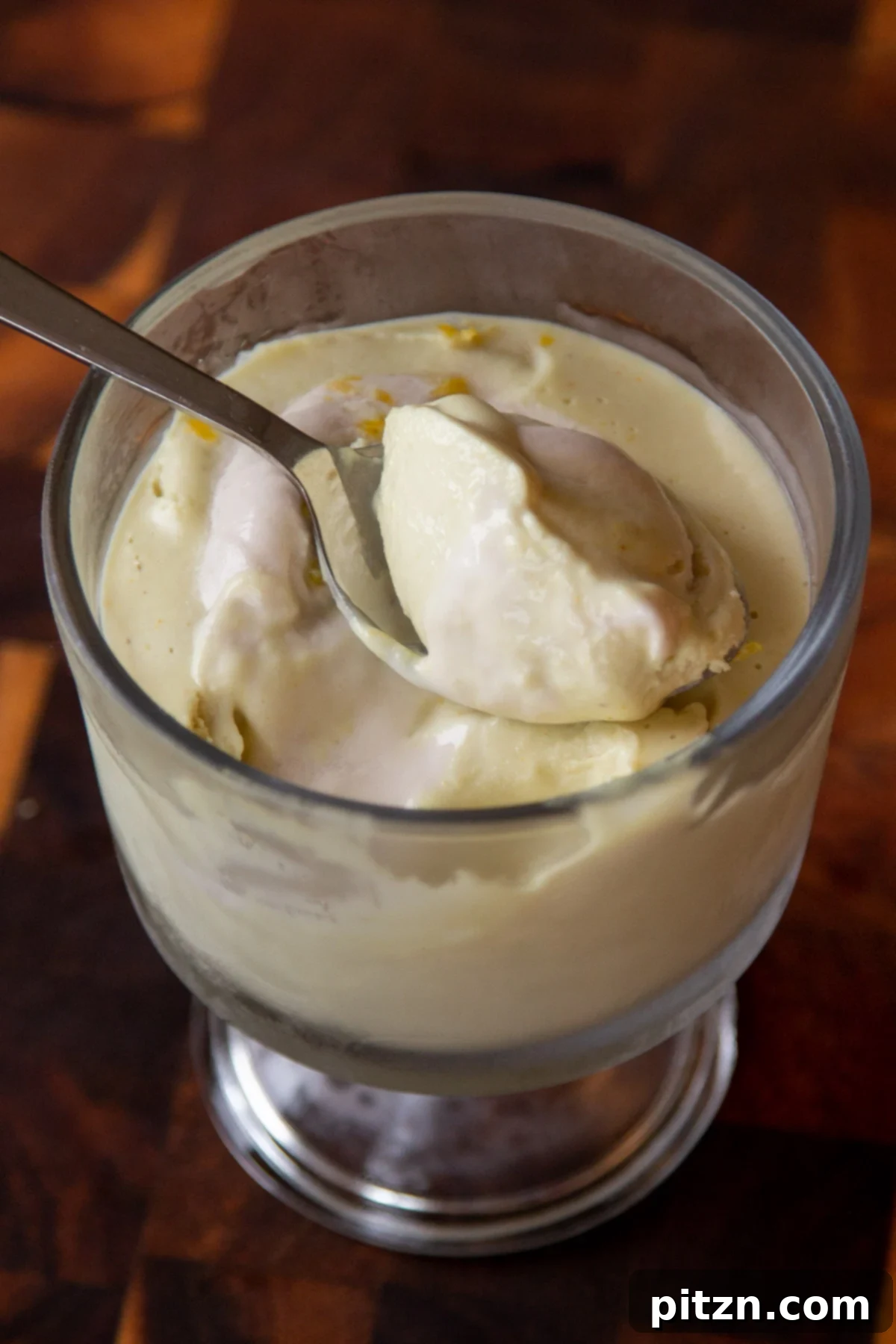 A cup of vegan lemon pudding with a spoon resting gently on its surface, ready to be enjoyed.