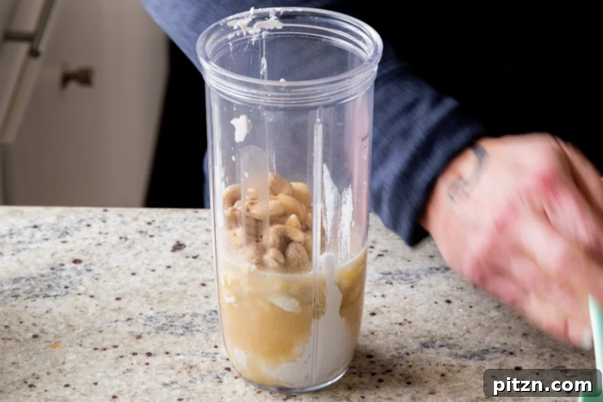 Soaked and drained cashews being added to a blender alongside other ingredients for vegan lemon pudding.