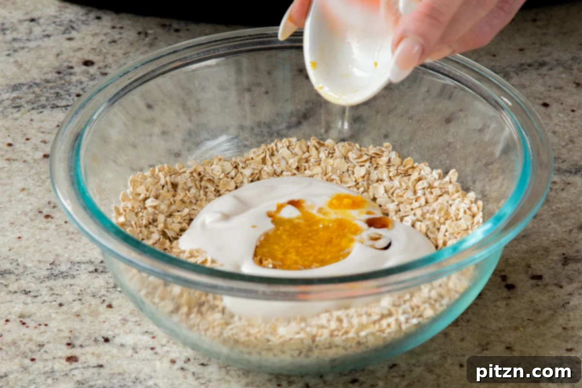 Easy Cannoli Overnight Oats: 30-Minute, Gluten-Free & Soy-Free 11 Fresh orange zest being added to the mixture of non-dairy yogurt, maple syrup, oats, and chia seeds in a glass bowl.