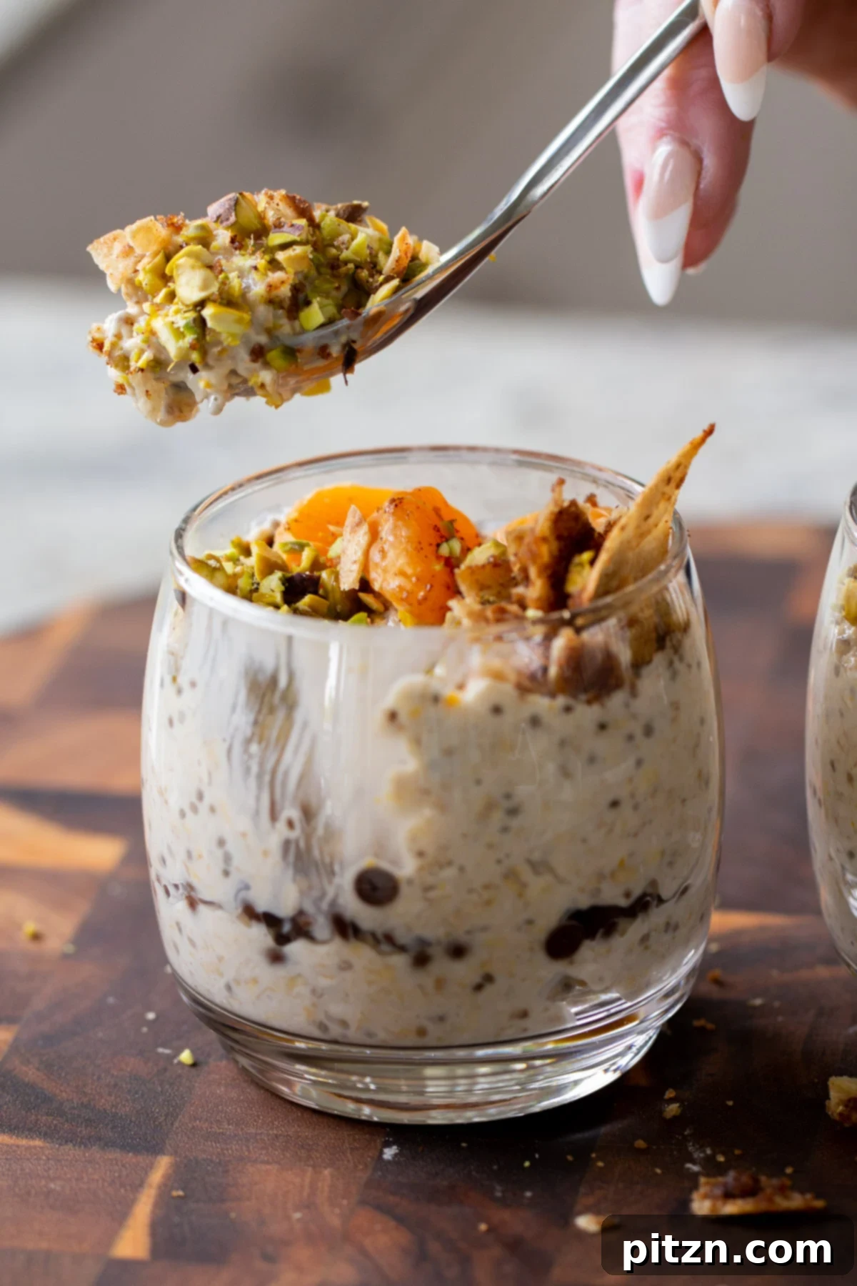 Easy Cannoli Overnight Oats: 30-Minute, Gluten-Free & Soy-Free 5 A spoon digging into a glass of Cannoli Overnight Oats, showcasing the creamy texture and chocolate chips within the oat mixture.