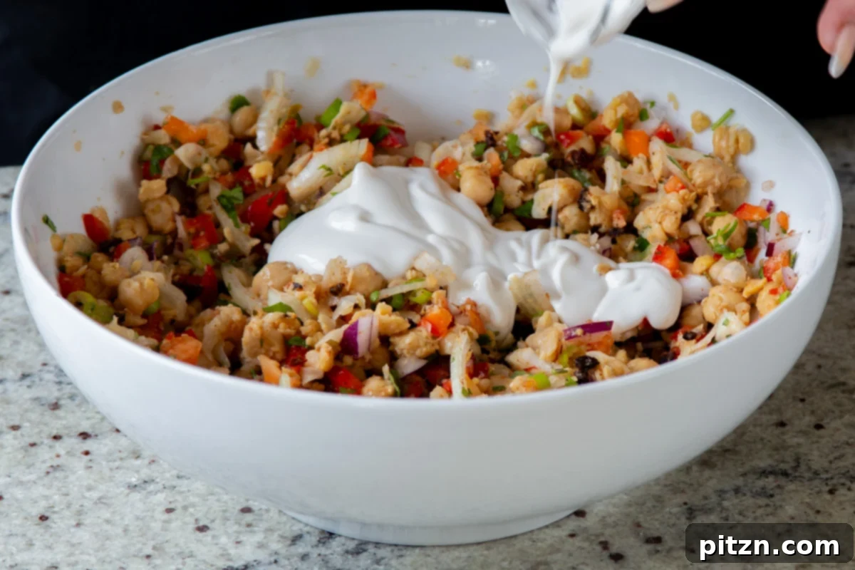 adding vegan yogurt and lime juice to the chickpea-veggie mixture