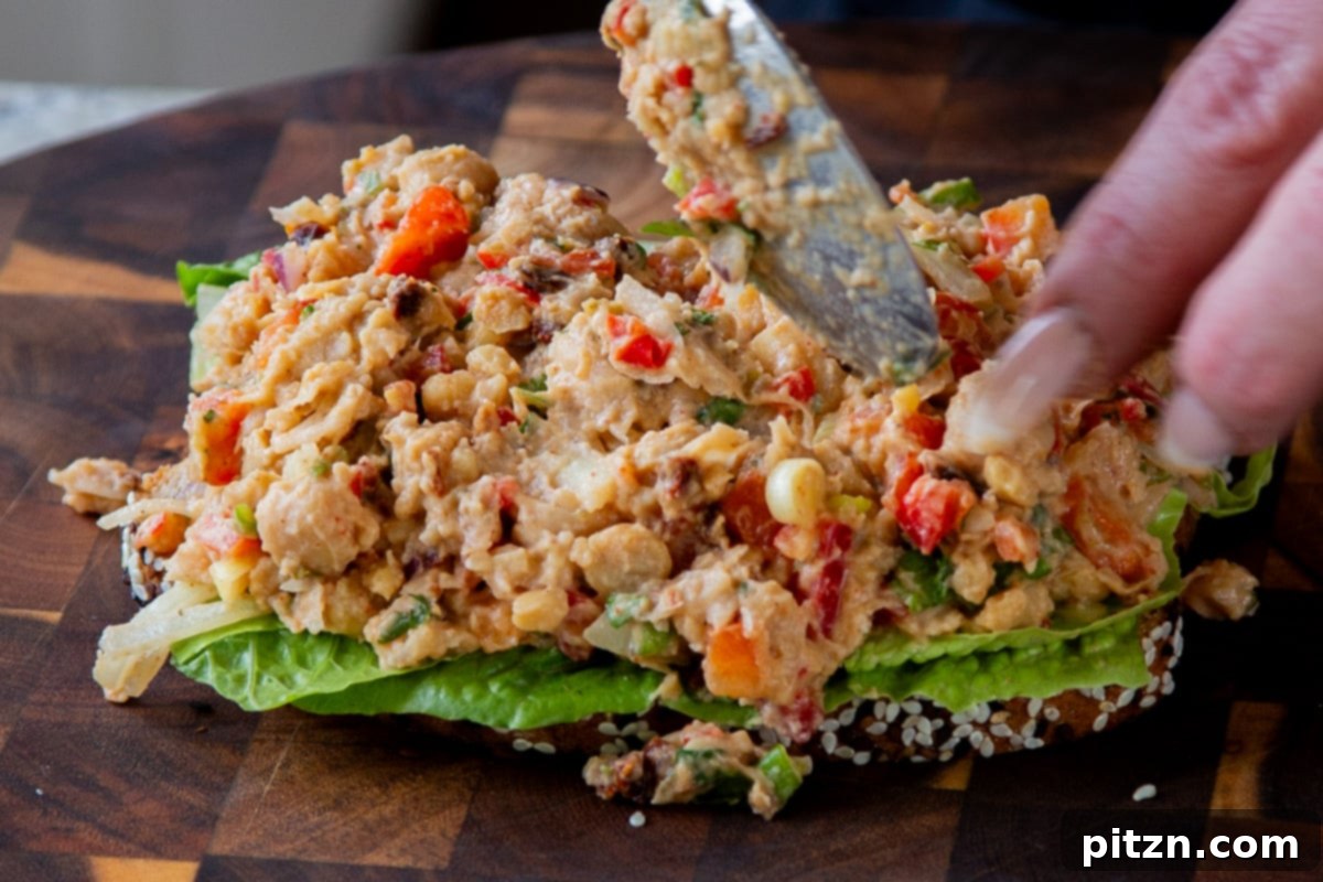 sponging cajun chickpea salad over the lettuce on the slice of bread