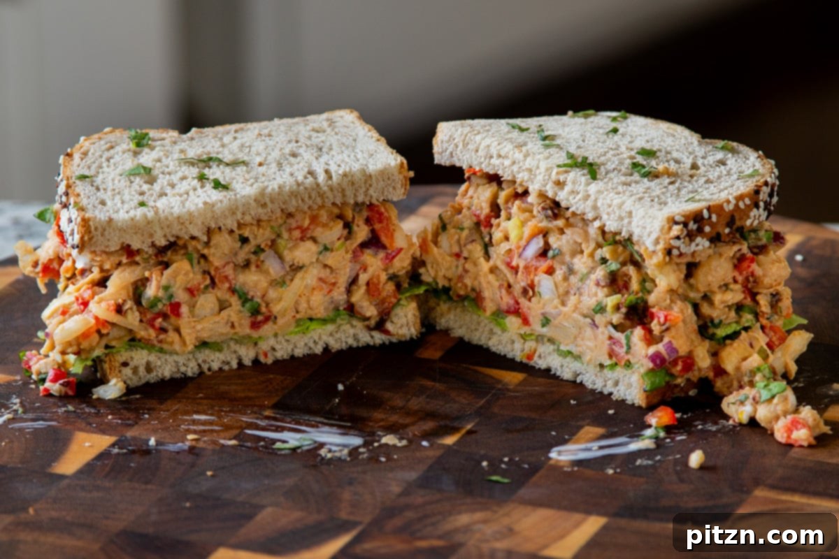 cajun chickpea salad sandwich sliced in half o a wooden cutting board