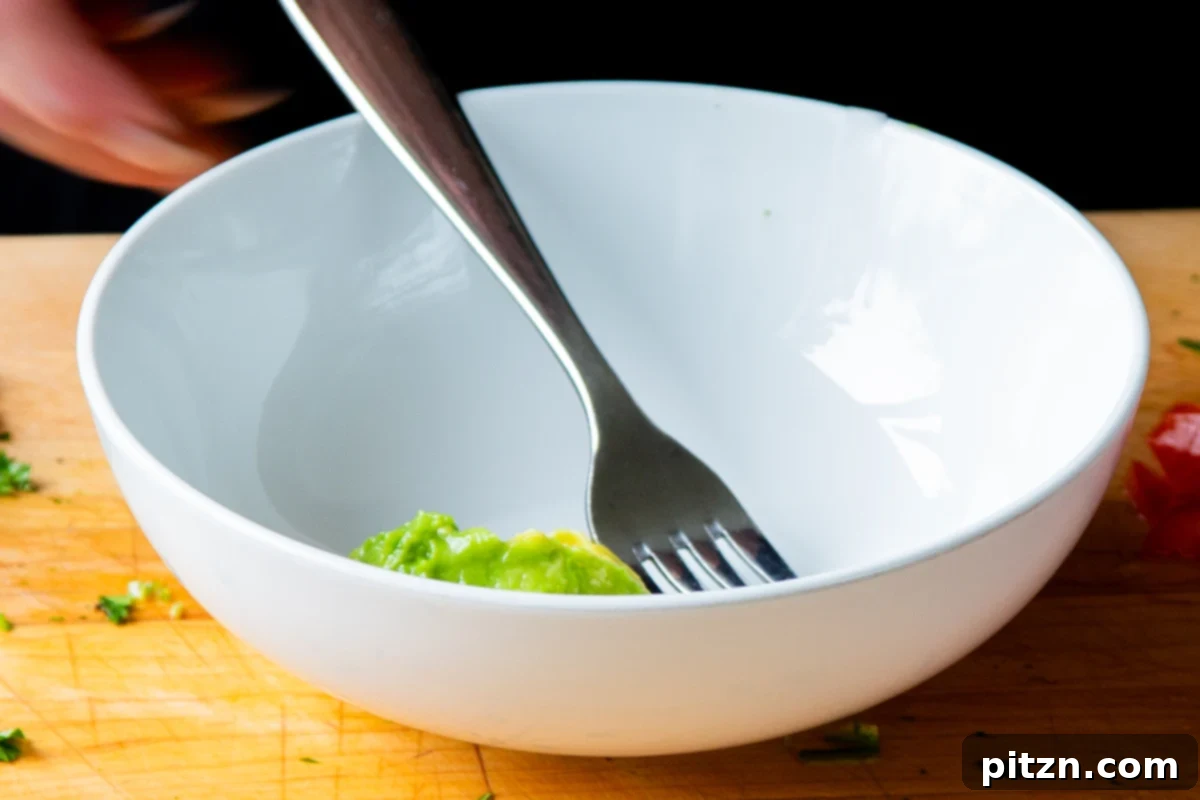 Crispy Quinoa Tacos: Effortlessly Allergy-Friendly 13 Mashing a ripe avocado in a bowl to make creamy guacamole for the tacos