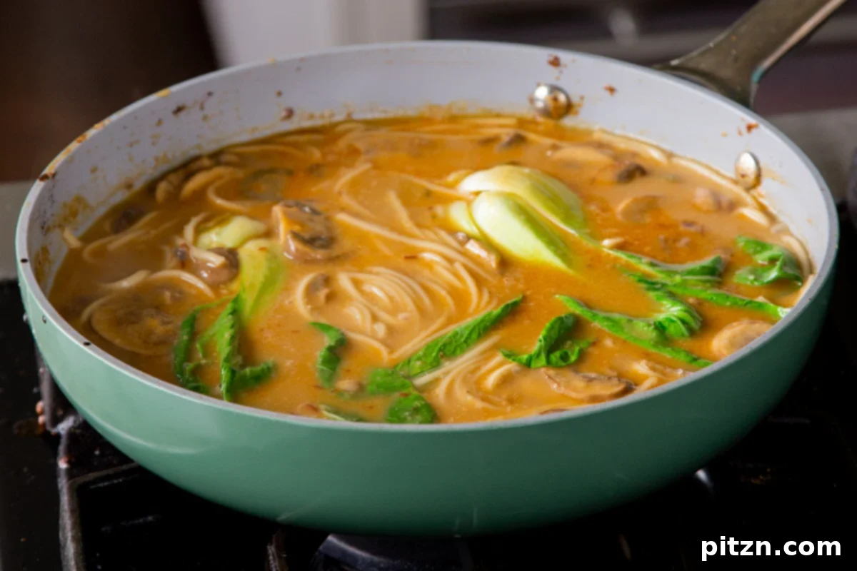 Cooked baby bok choy in the ramen broth, showing its vibrant green color and perfectly tender texture after a short simmer, ready to serve.
