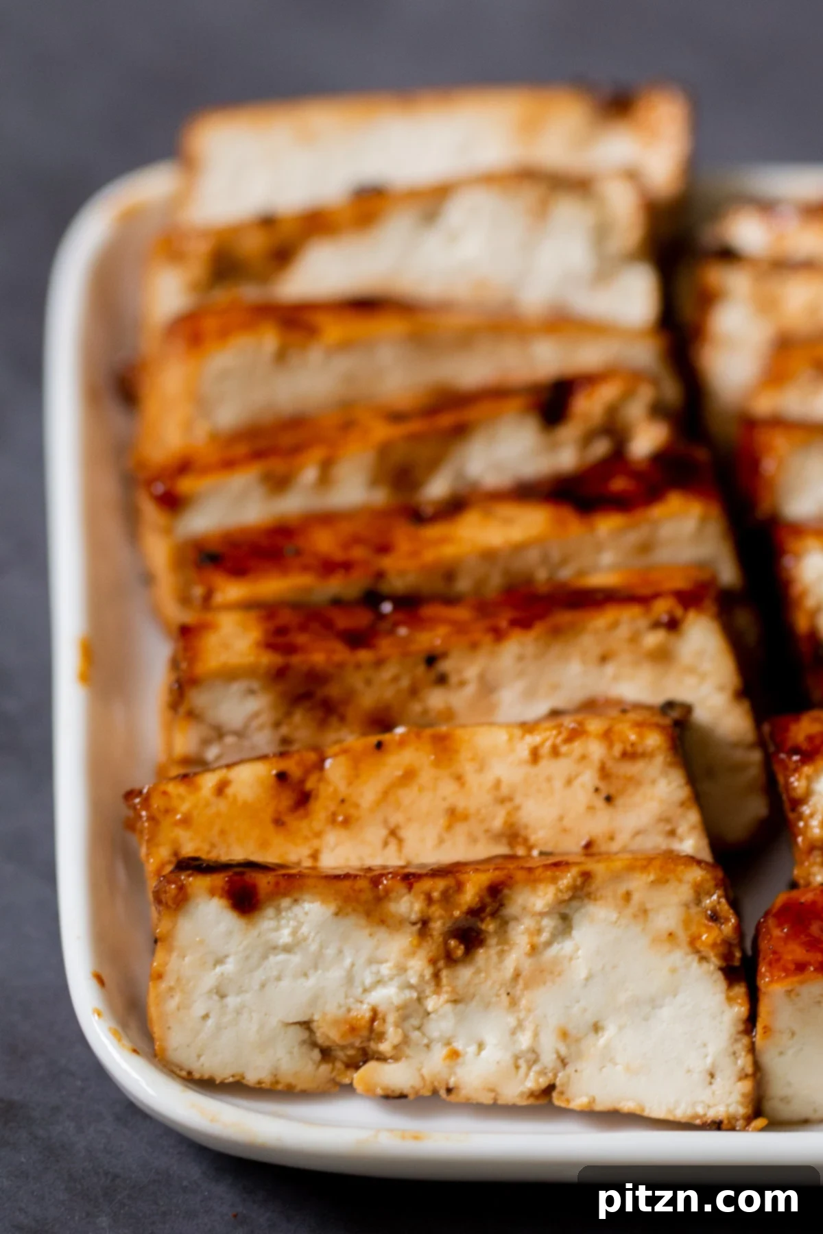 Macro shot of perfectly seared and glazed char siu tofu slices arranged artfully on a pristine white plate, ready to top ramen.