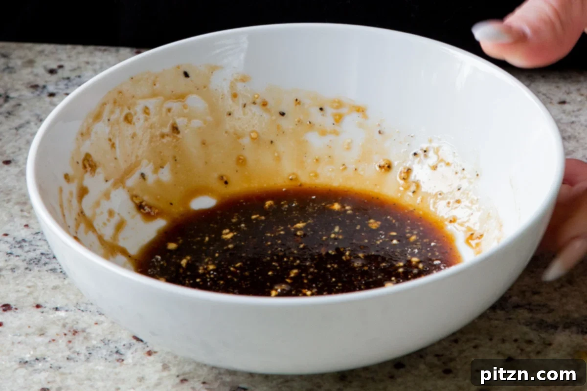 The tofu marinade in a bowl, after all ingredients have been thoroughly mixed to create a smooth, dark, and aromatic sauce for the tofu.