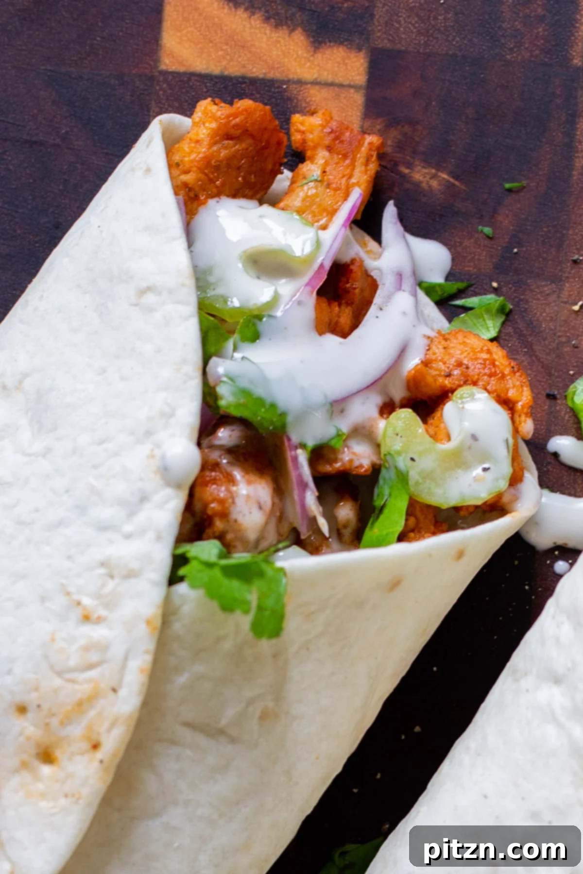 Zesty 30-Minute Cajun Buffalo Soy Curl Wraps 2 Close-up of a perfectly rolled Buffalo Cajun Soy Curl Wrap, showcasing the golden-brown soy curls and fresh green filling inside.