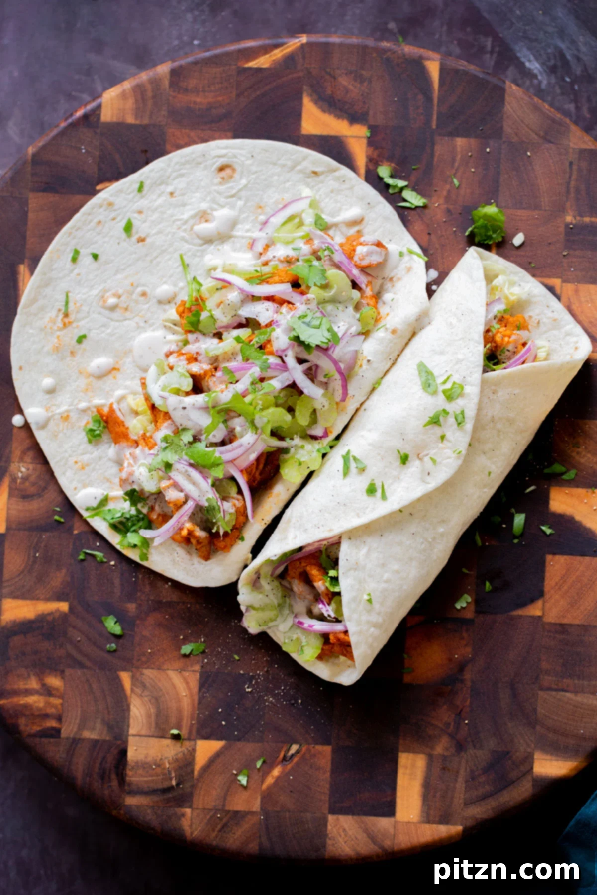 Zesty 30-Minute Cajun Buffalo Soy Curl Wraps 3 Two vibrant vegan Buffalo Cajun wraps, one expertly closed and the other invitingly open, revealing its rich and colorful filling of soy curls and fresh vegetables.
