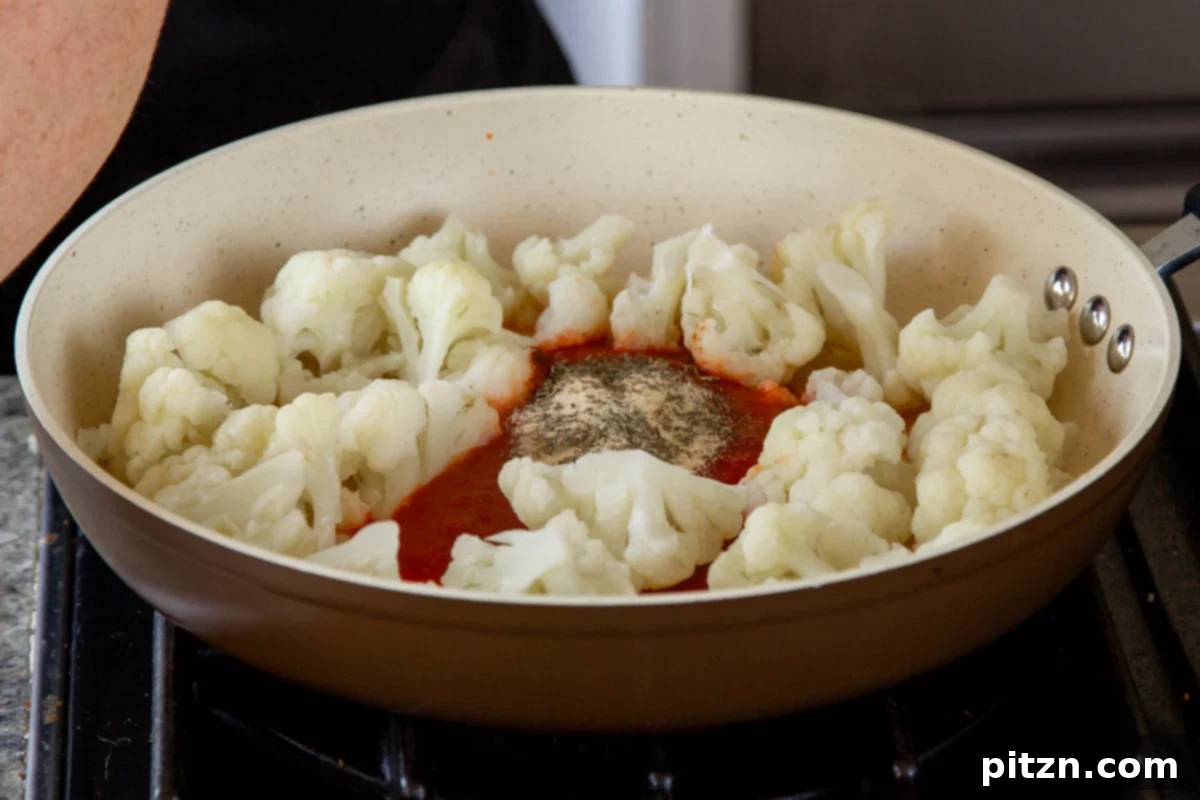 Spicy Harissa Roasted Cauliflower with Creamy Tahini Dill 9 adding harissa paste and spices to the partially-cooked cauliflower in a skillet