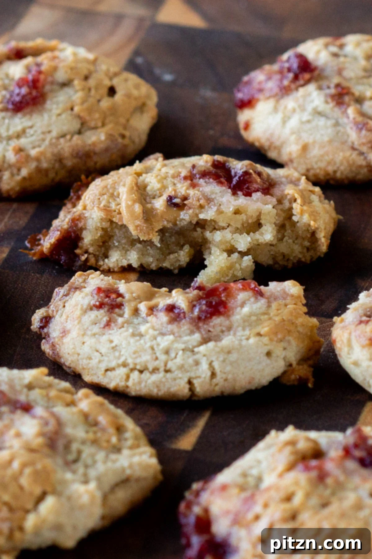 Easy One-Bowl 30-Minute Gluten-Free PB and J Cookies 2 Close-up of a gluten-free peanut butter and jelly cookie broken in half, revealing its tender texture and delicious filling.