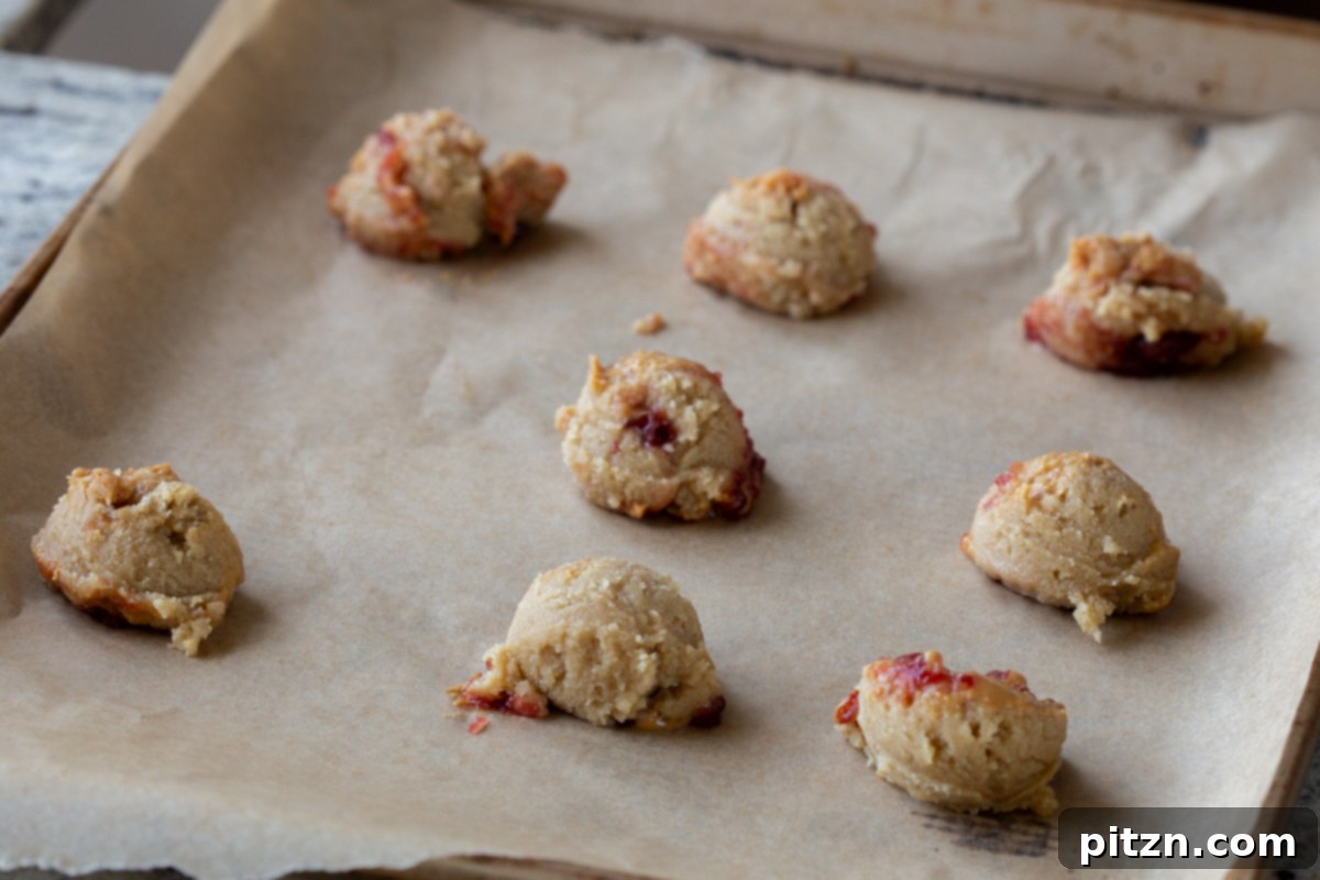 Easy One-Bowl 30-Minute Gluten-Free PB and J Cookies 12 Unbaked cookies, perfectly scooped and arranged on the baking sheet, awaiting the oven.