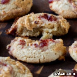 Easy One-Bowl 30-Minute Gluten-Free PB and J Cookies 5 Close-up of a gluten-free peanut butter and jelly cookie broken in half, showcasing its interior.