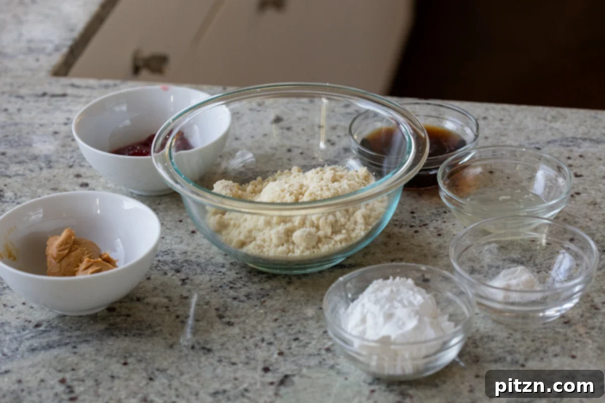 Easy One-Bowl 30-Minute Gluten-Free PB and J Cookies 6 Almond flour, peanut butter, jam, and other cookie ingredients laid out in bowls on a clean kitchen counter.