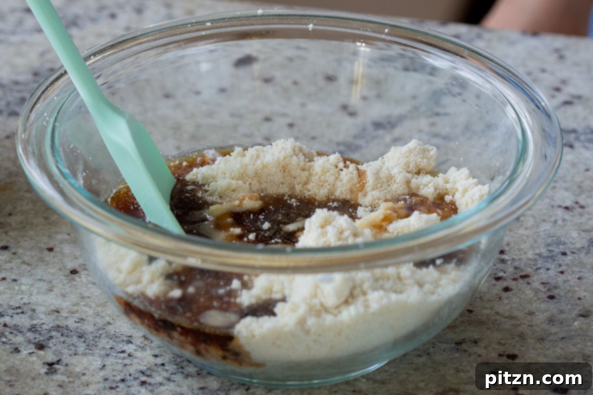 Easy One-Bowl 30-Minute Gluten-Free PB and J Cookies 9 Maple syrup, coconut oil, and vanilla extract being added to the mixed dry ingredients.