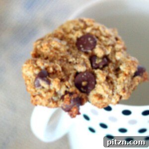 Oatmeal chocolate chip cookie resting on a mug, ready to be enjoyed with a warm drink.