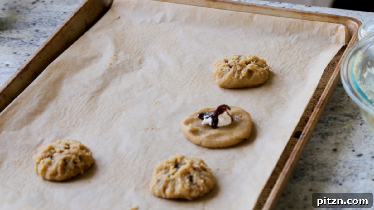 Drizzling coffee caramel sauce over the vegan cream cheese filling in a flattened Tiramisu Cookie on a baking sheet.
