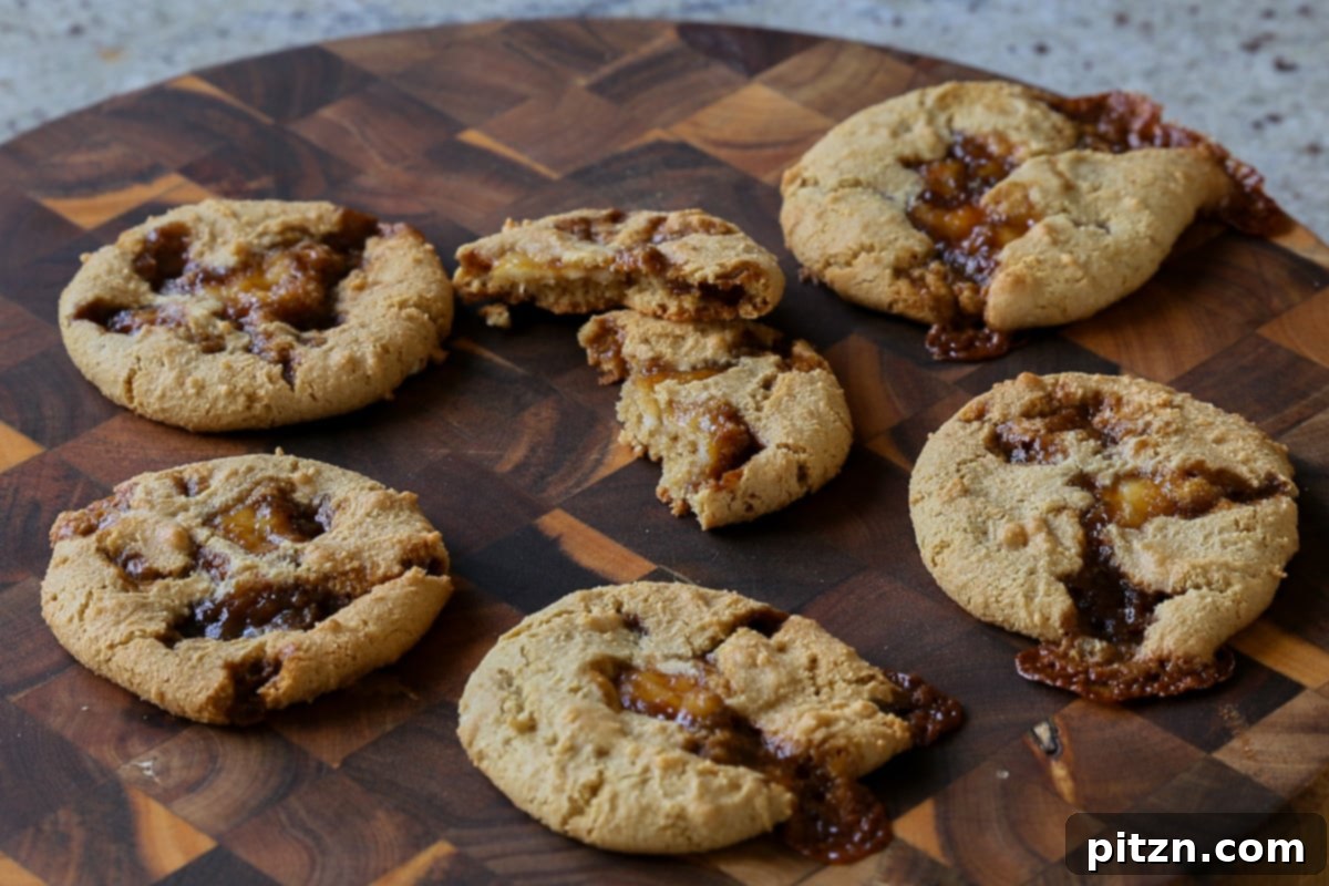 Freshly baked Tiramisu Cookies on a wooden cutting board, with one cookie broken open to reveal its delightful creamy and caramel filling.