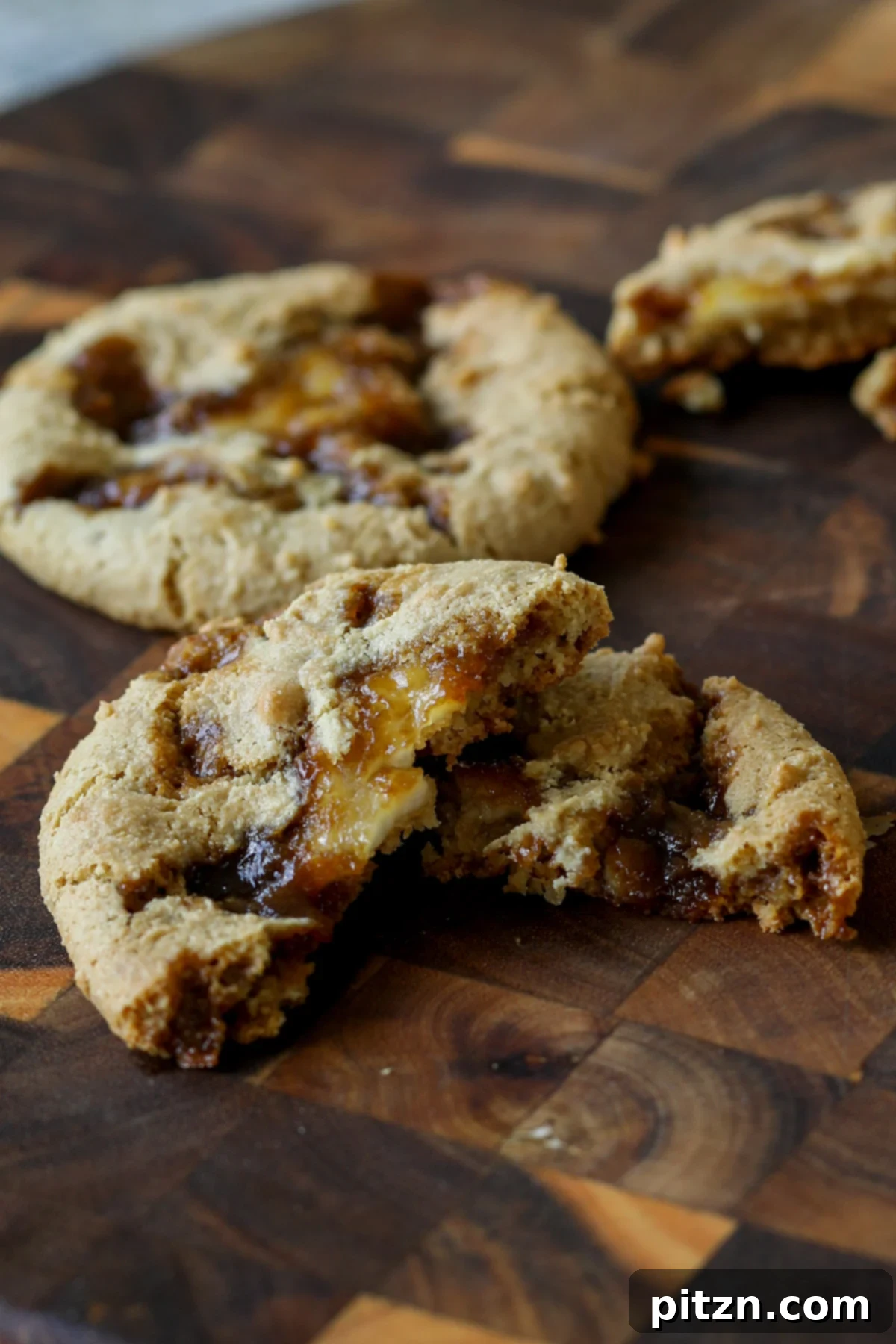 A Tiramisu Cookie elegantly broken in half on a cutting board, revealing the luscious layers of coffee caramel and vegan cream cheese filling within its soft, grain-free base.