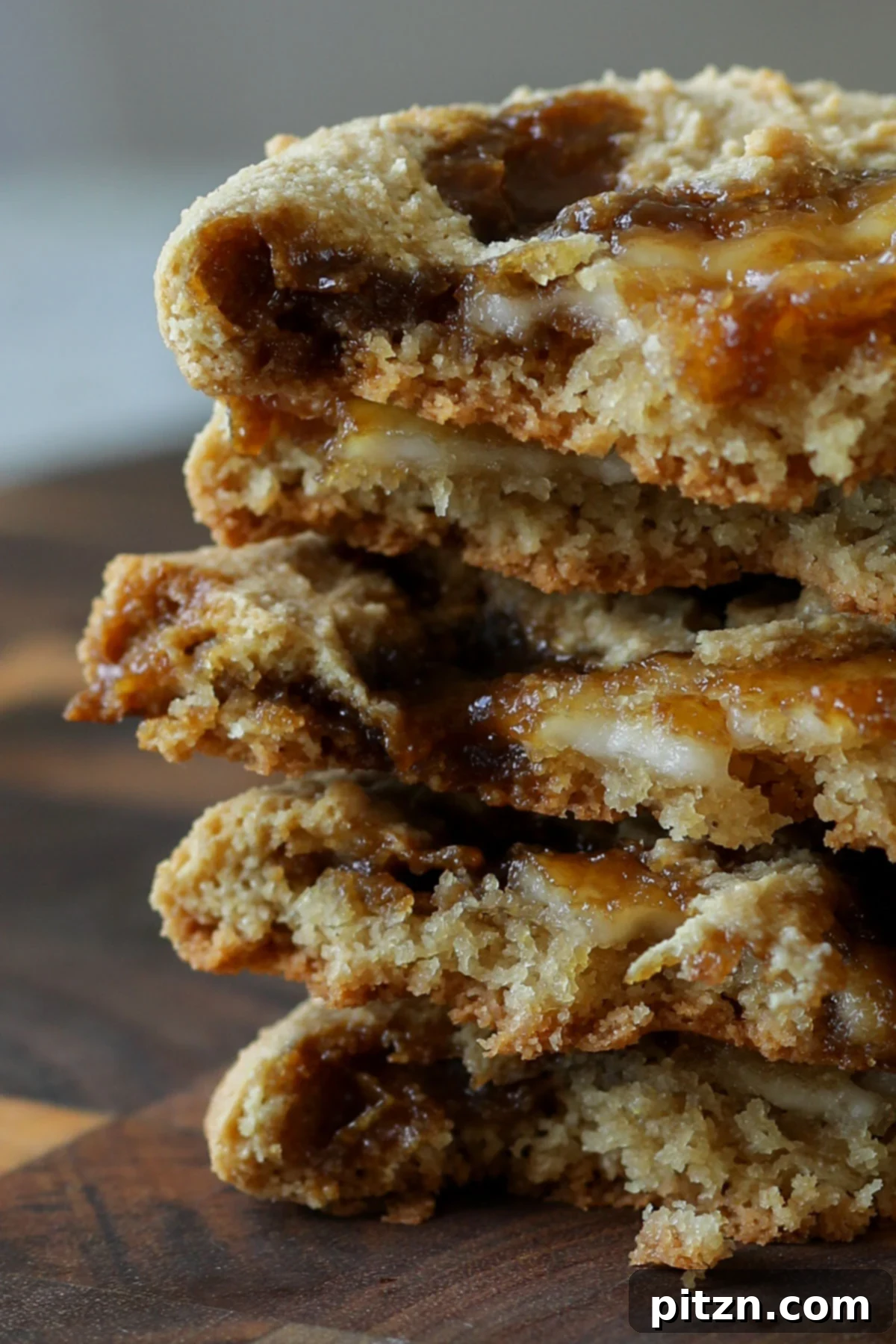 A stack of beautifully halved Tiramisu Cookies, showcasing their layered interior with coffee-infused cookie, creamy vegan cheese, and glistening coffee-caramel.