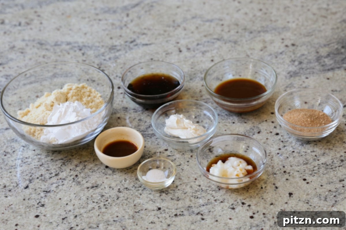 Various Tiramisu Cookie ingredients laid out in bowls on a kitchen counter, including almond flour, maple syrup, coffee, and coconut oil, ready for baking.
