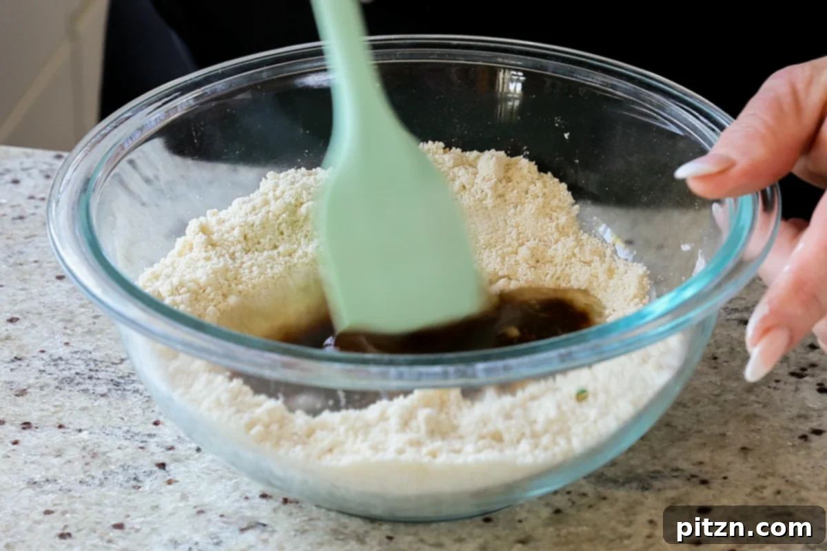 Adding liquid ingredients to the mixed dry ingredients in a bowl to form the Tiramisu Cookie dough.