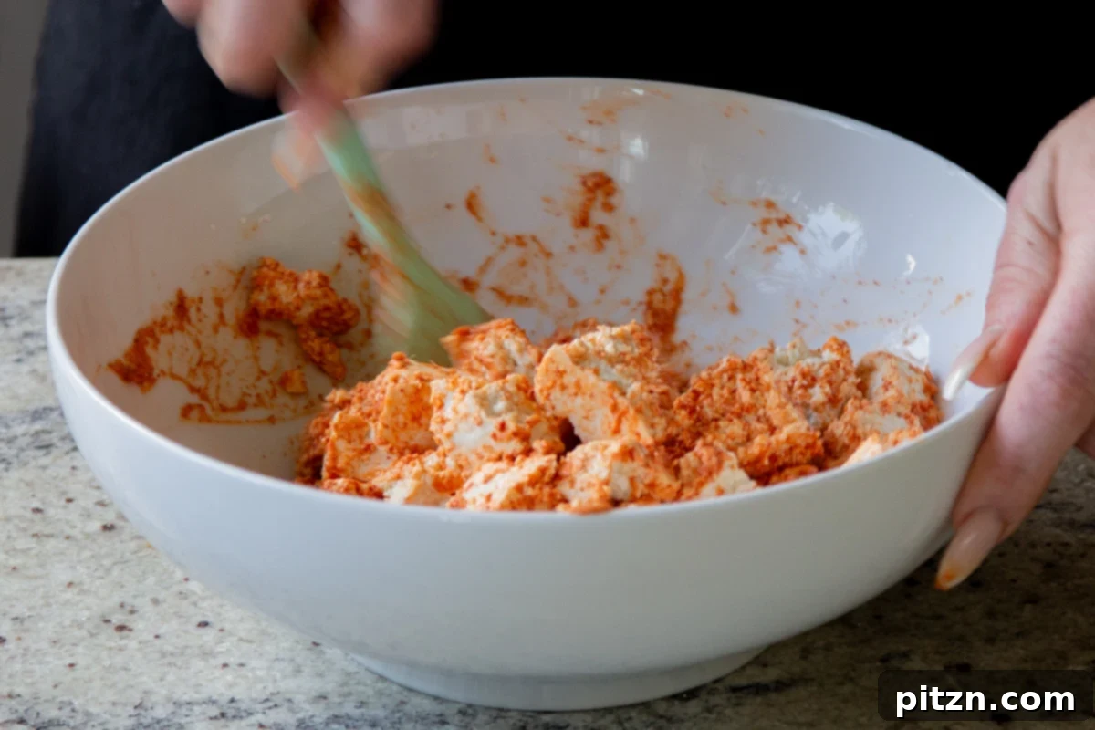 Tofu pieces thoroughly tossed with the seasoned yogurt mixture, coated and ready for cooking.