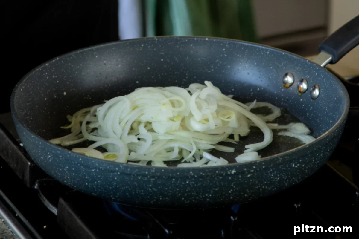 Adding sliced red onion and salt to the pan, beginning the caramelization process.