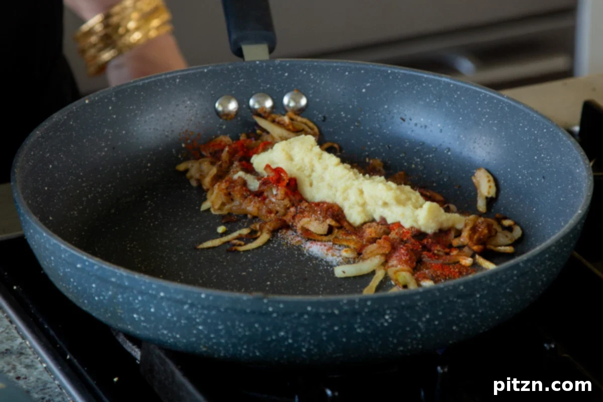 Adding ginger-garlic paste to the sautéed onions, infusing the base with aromatic intensity.
