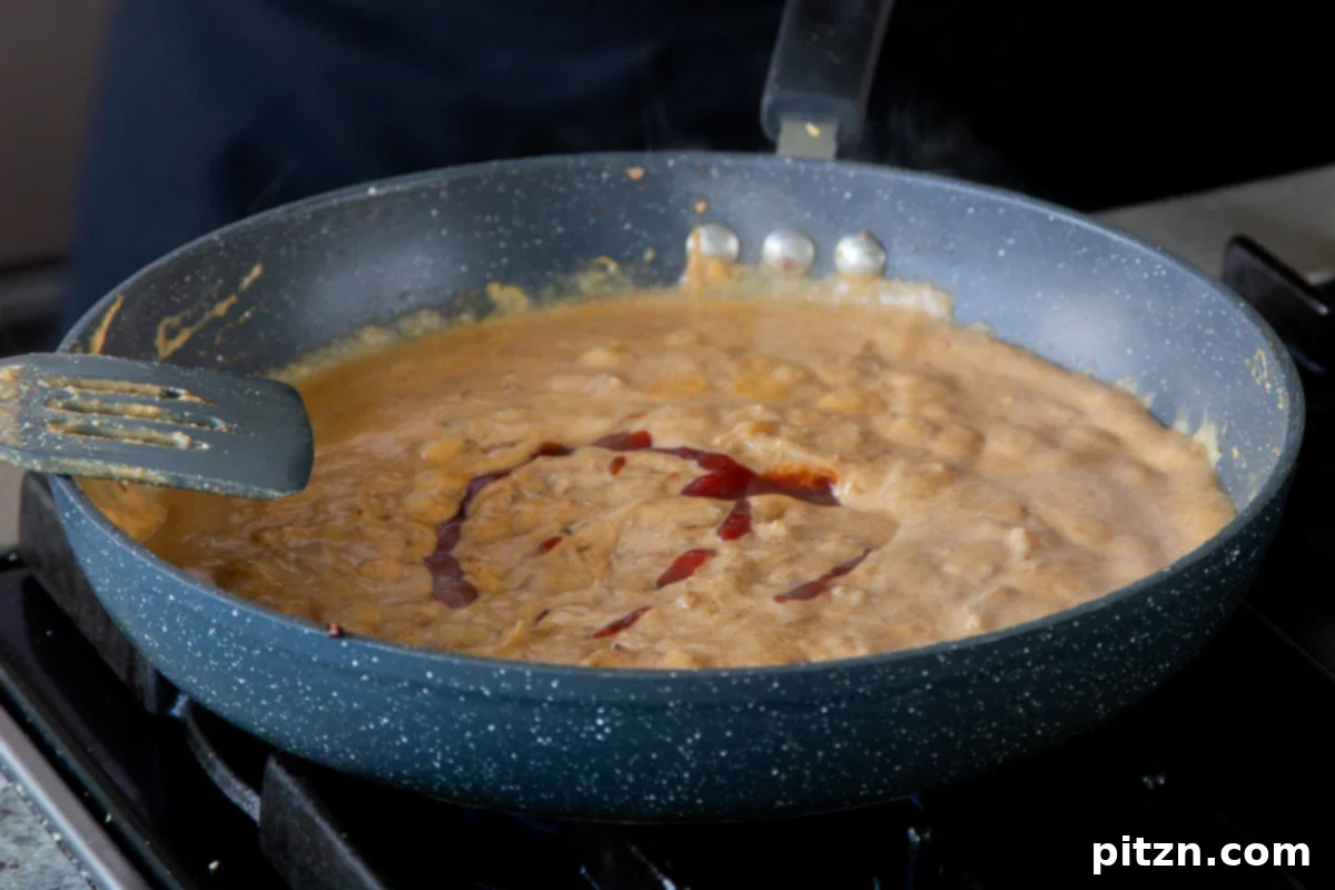 Adding rich tomato paste to the sauce, deepening its color and savory notes.