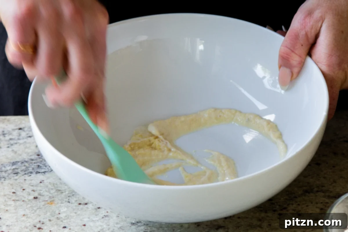 Mixing ginger-garlic paste and non-dairy yogurt in a bowl, forming a smooth marinade base.