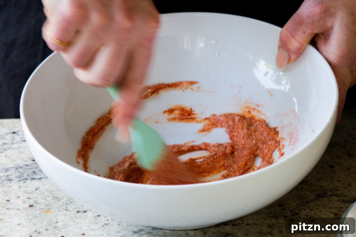 Adding Kashmiri chili powder to the yogurt mixture, enhancing its color and flavor.