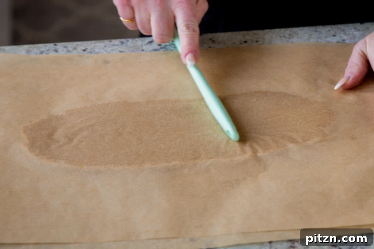 rolling out almond flour cookie dough between 2 pieces of parchment paper for even thickness
