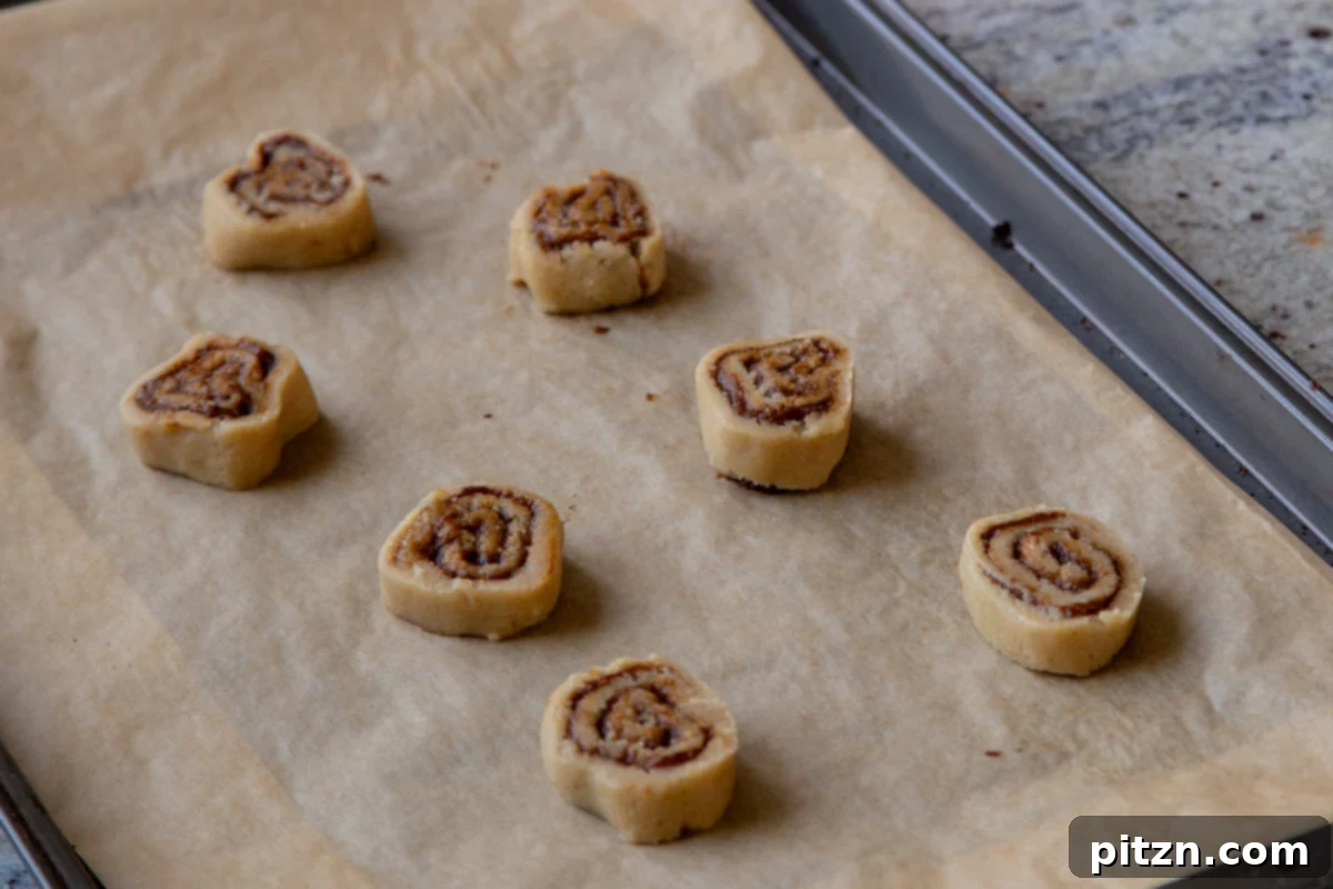slices of the cookie dough on a baking sheet, ready to bake, showing the clear pumpkin spice spirals