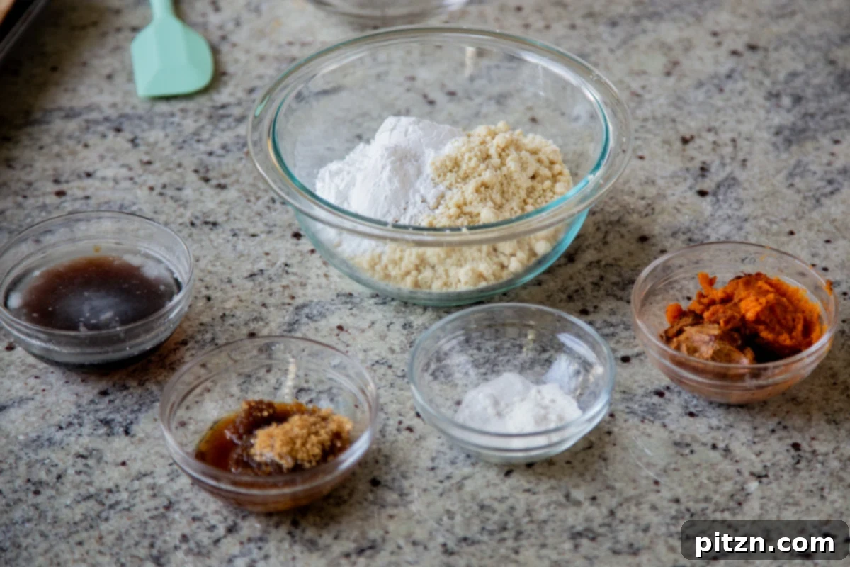 almond flour, tapioca starch, and other cookie ingredients in bowls on a kitchen counter, showcasing the simple components of these gluten-free pumpkin cookies