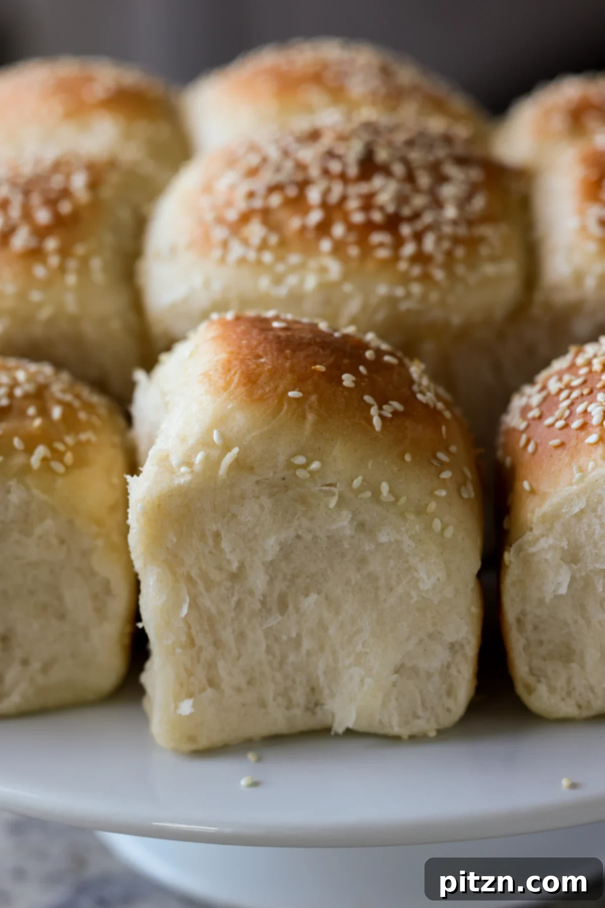 Melt-in-Your-Mouth Dinner Rolls 2 fluffy dinner rolls on a serving tray after pulling apart