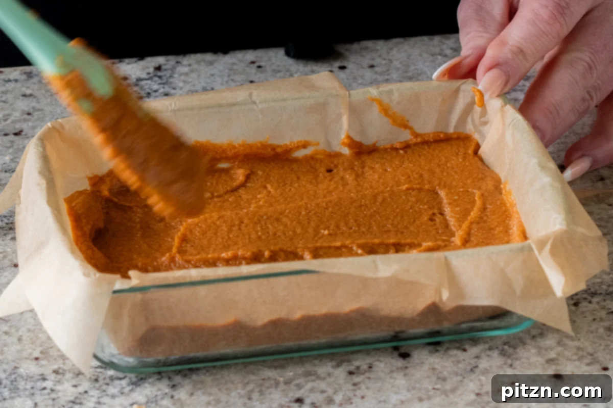 evening out the top of the pumpkin crisp filling in the lined baking pan