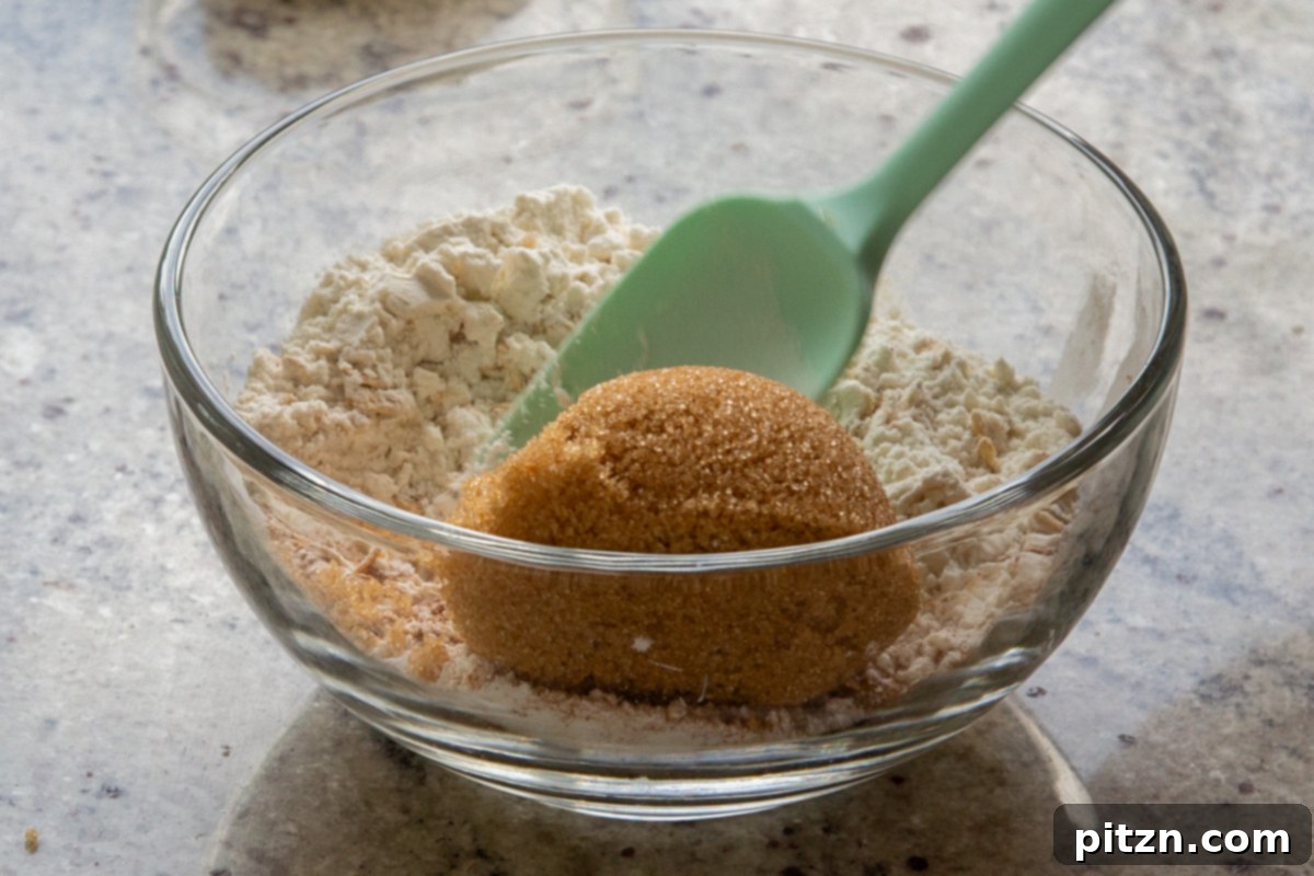 adding brown sugar to the bowl of oats, flour, and spices