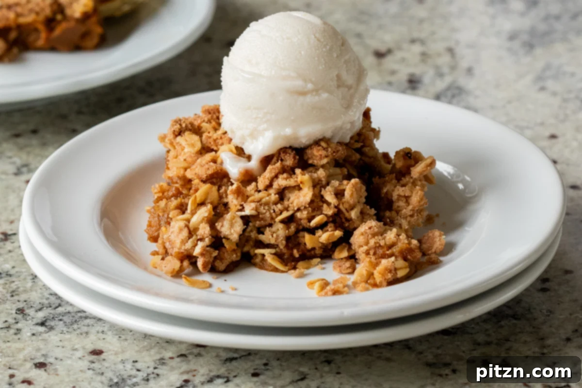 slice of pumpkin crisp on a white plate with ice cream on top