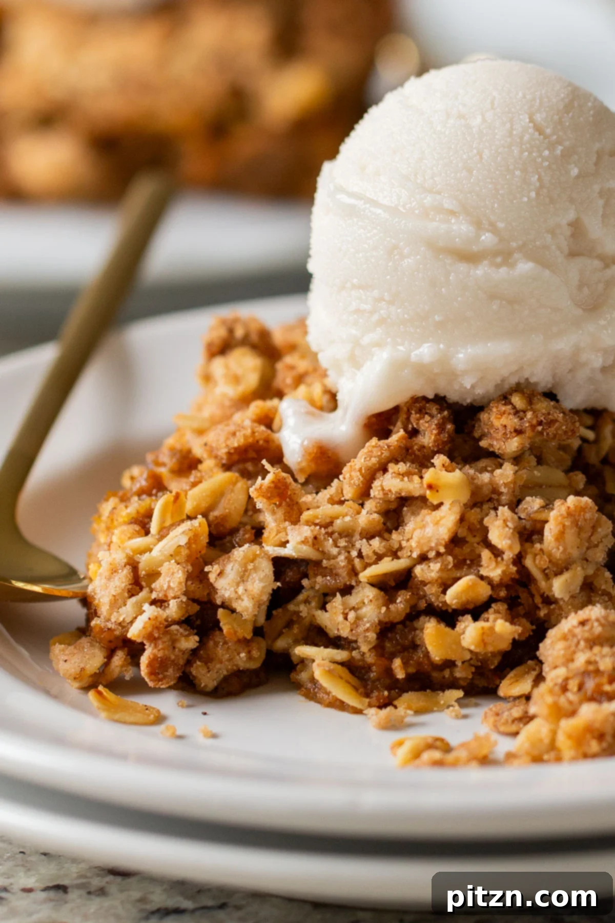 close-up of slice of pumpkin crisp on a white plate with ice cream on top