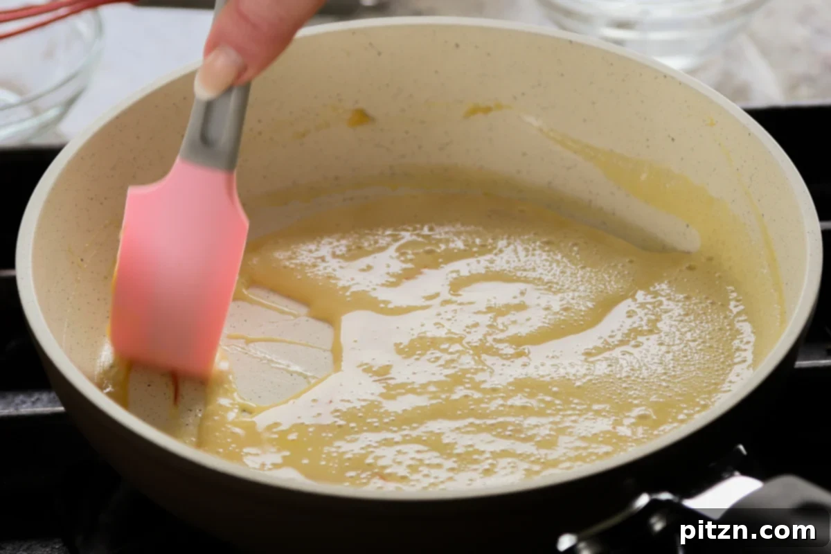 The saffron custard in the saucepan after cooking, appearing thick and creamy, ready to be cooled.