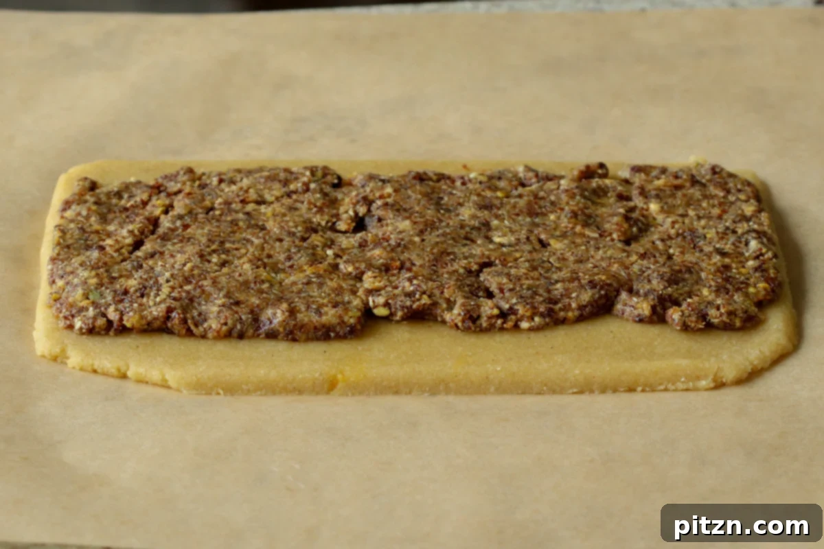 The peda dough rolled out, with the vibrant Gujiya filling spread evenly on top, leaving a border.