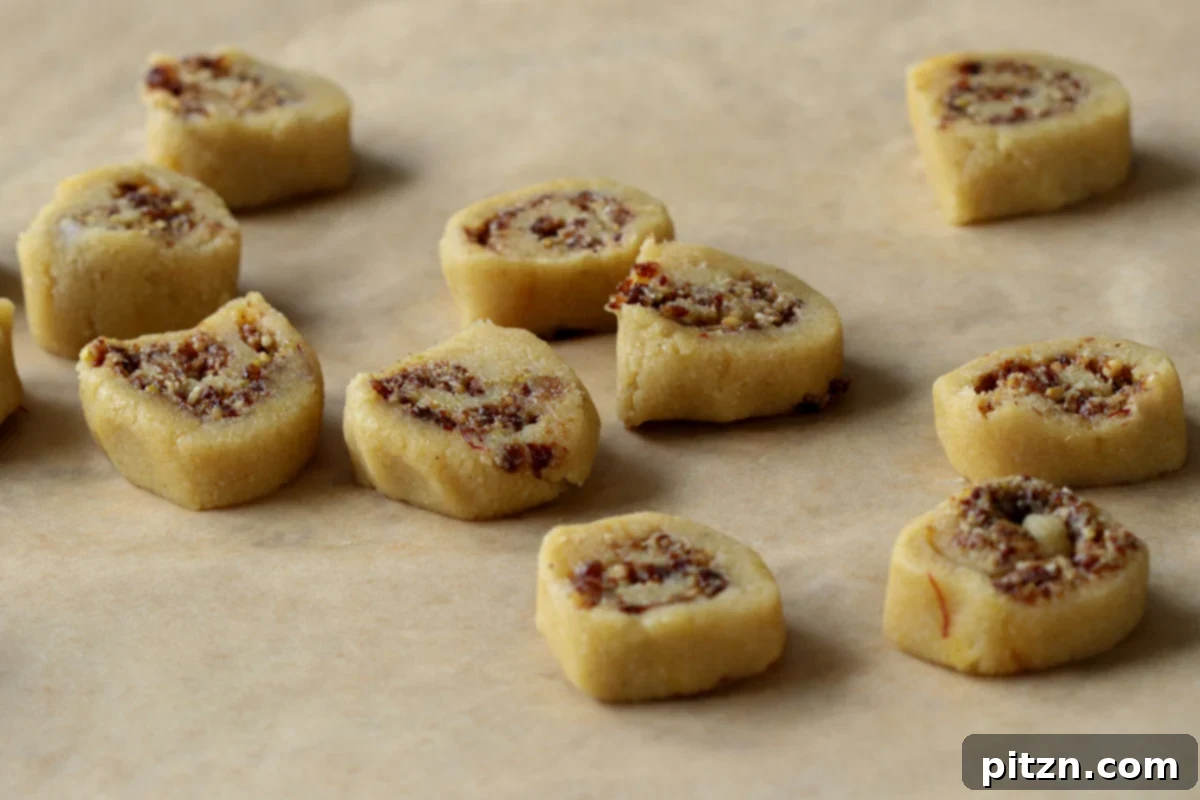 Sliced Gujiya Peda pieces arranged on a piece of parchment paper, revealing their perfect pinwheel swirls.