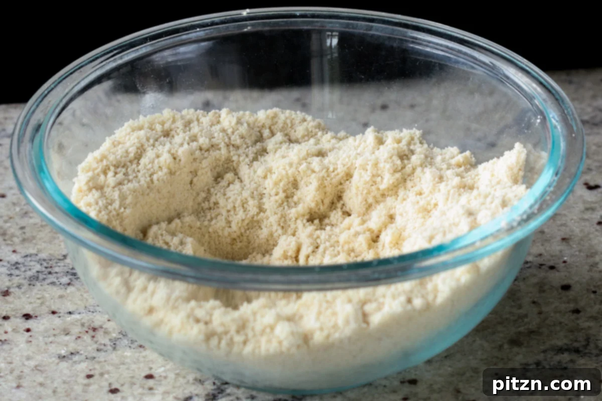 A bowl containing blanched almond flour, powdered sugar, cardamom, and salt, ready to be mixed for the peda base.
