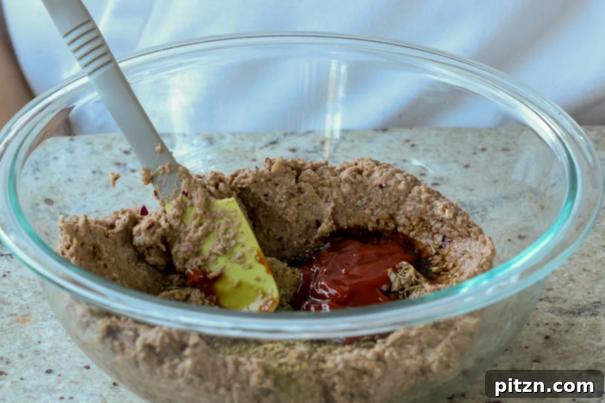 Ultimate Gluten-Free Vegan Wellington 14 Adding sauces and seasonings to the lentil mixture in the bowl, ensuring all components are well combined for optimal flavor.