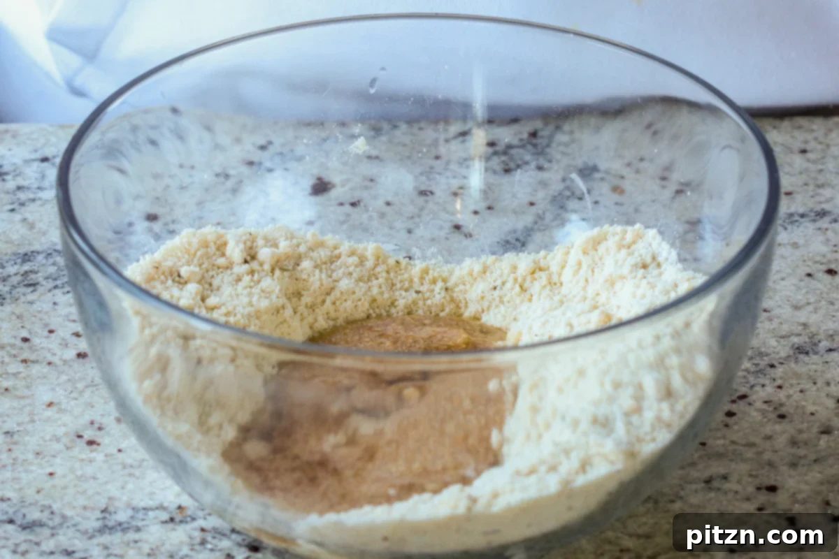Ultimate Gluten-Free Vegan Wellington 21 Wet ingredients, including flax egg, coconut oil, and maple syrup, being added to the dry crust mixture in a bowl.