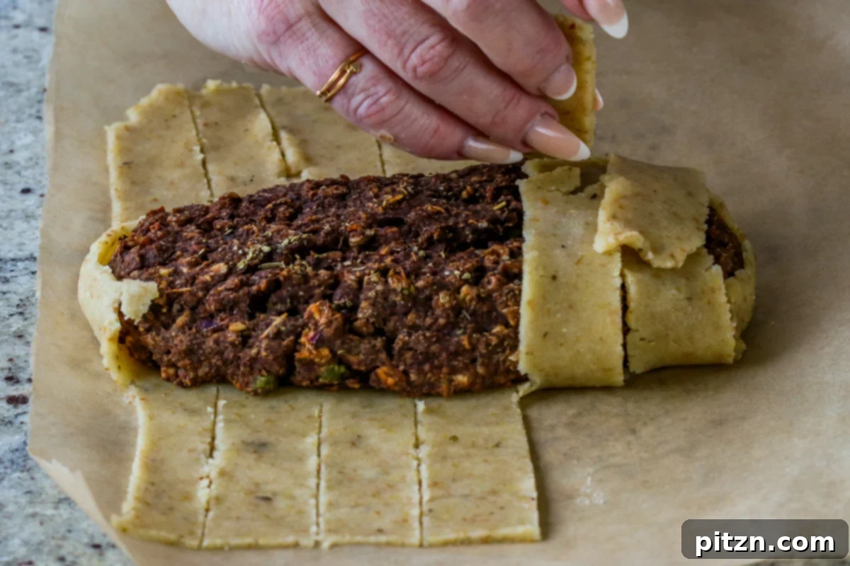 Ultimate Gluten-Free Vegan Wellington 28 Beginning the wrapping process, with ribbons of dough being folded over the lentil loaf to create the Wellington's pastry crust.
