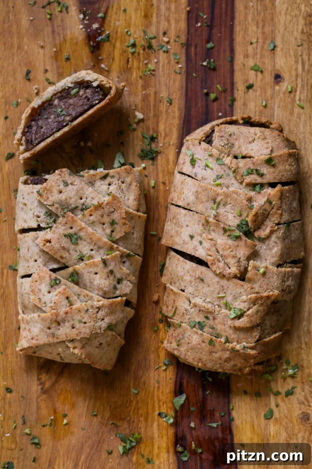 Ultimate Gluten-Free Vegan Wellington 5 Freshly baked and sliced Gluten-Free Vegan Wellington on a cutting board, highlighting the texture of the lentil loaf and the crispiness of the crust.
