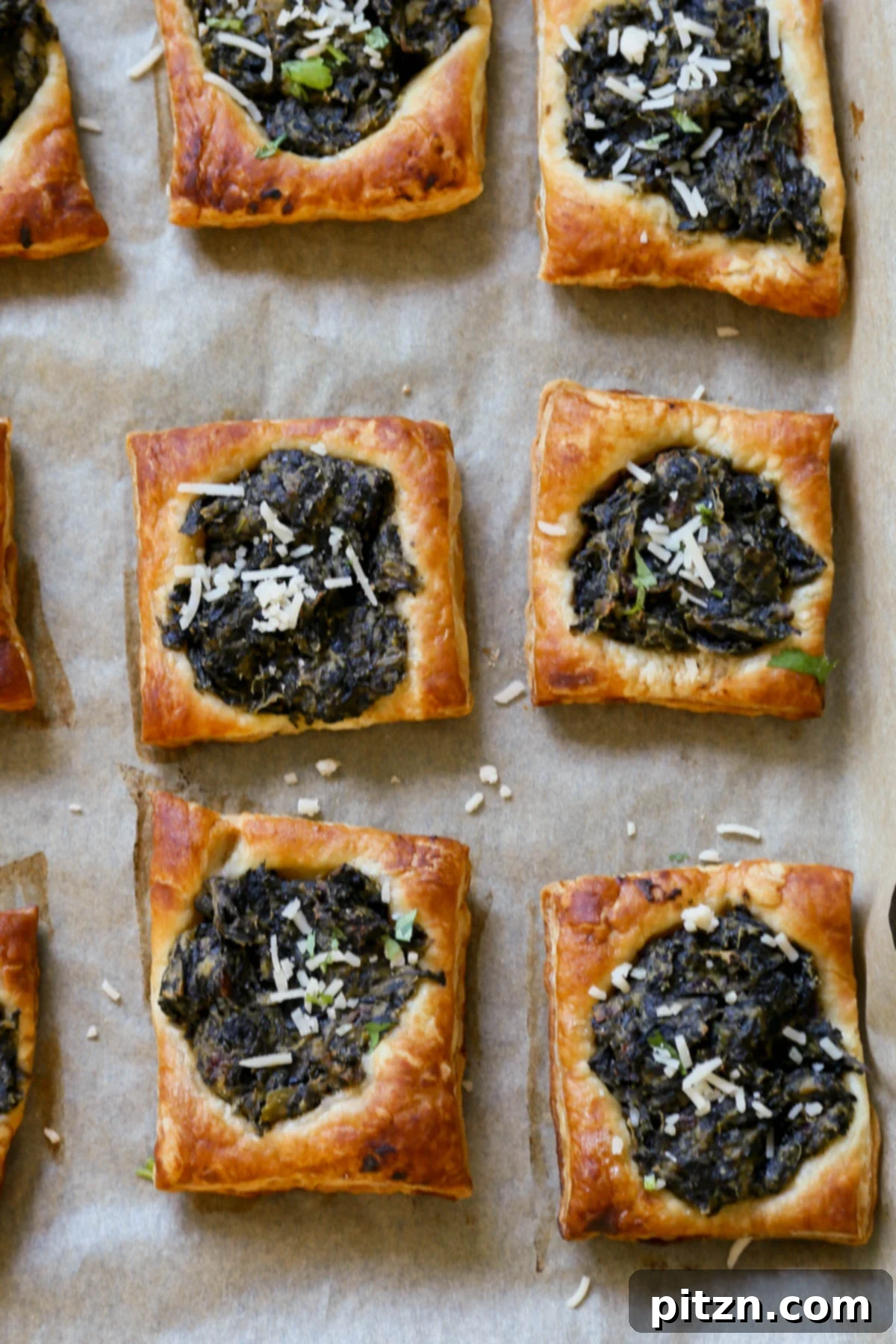 Freshly baked Indian-spiced spinach puff pastries cooling on a baking sheet, showcasing their golden-brown edges and richly textured spinach filling.