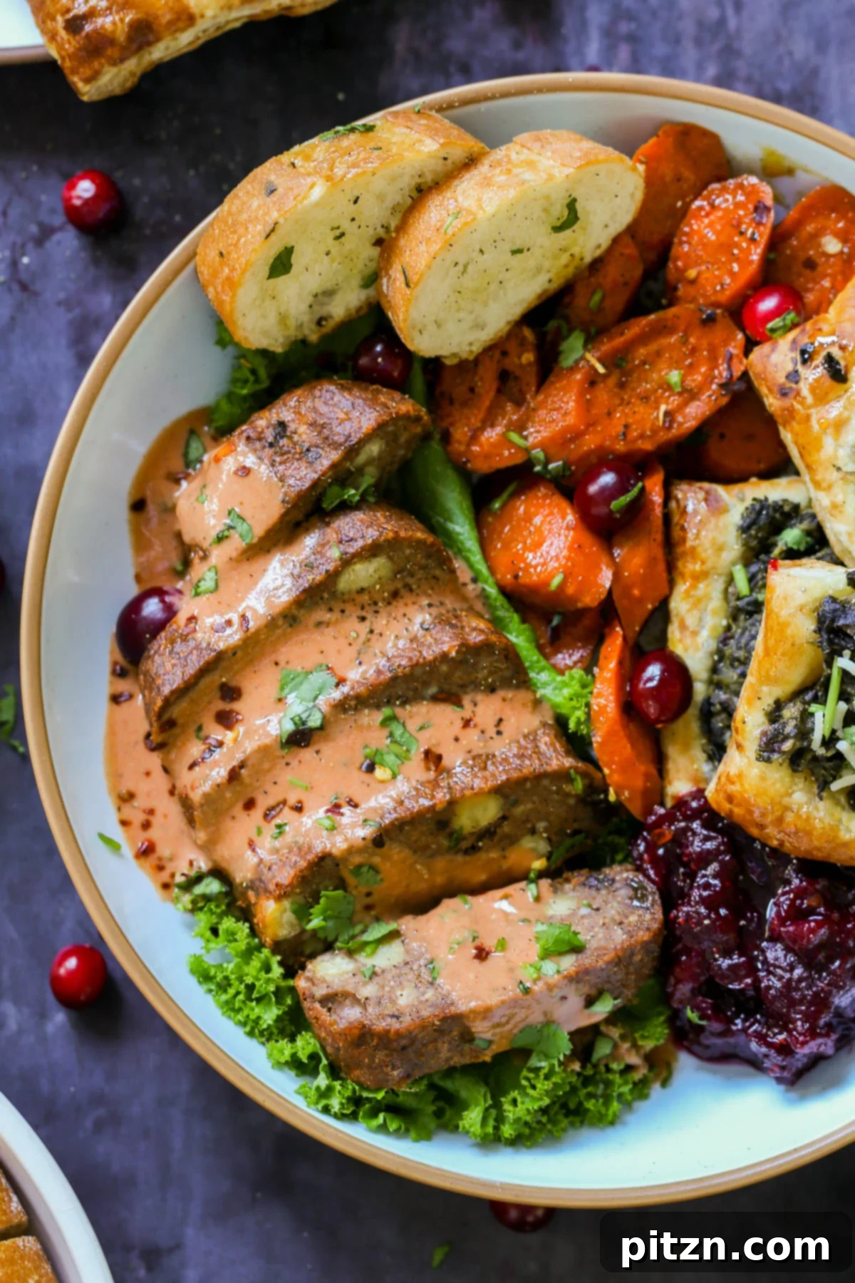 A beautifully presented Indian spiced chickpea pecan meatloaf slice on a plate, surrounded by a vibrant vegan Indian Thanksgiving spread with butter gravy.